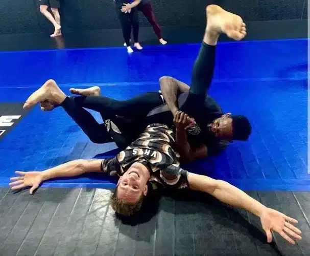 Two people in Gi and No Gi BJJ demonstrating a technique