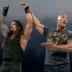 The Rock lifting Roman Reigns' right arm in victory prior to his announcement of the match with The Rock v. Roman Reigns At WrestleMania XL
