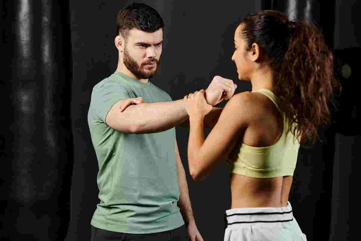 Best Form of Martial Arts for Self-Defense: A male trainer teaches self-defense techniques to a woman in a gym setting.