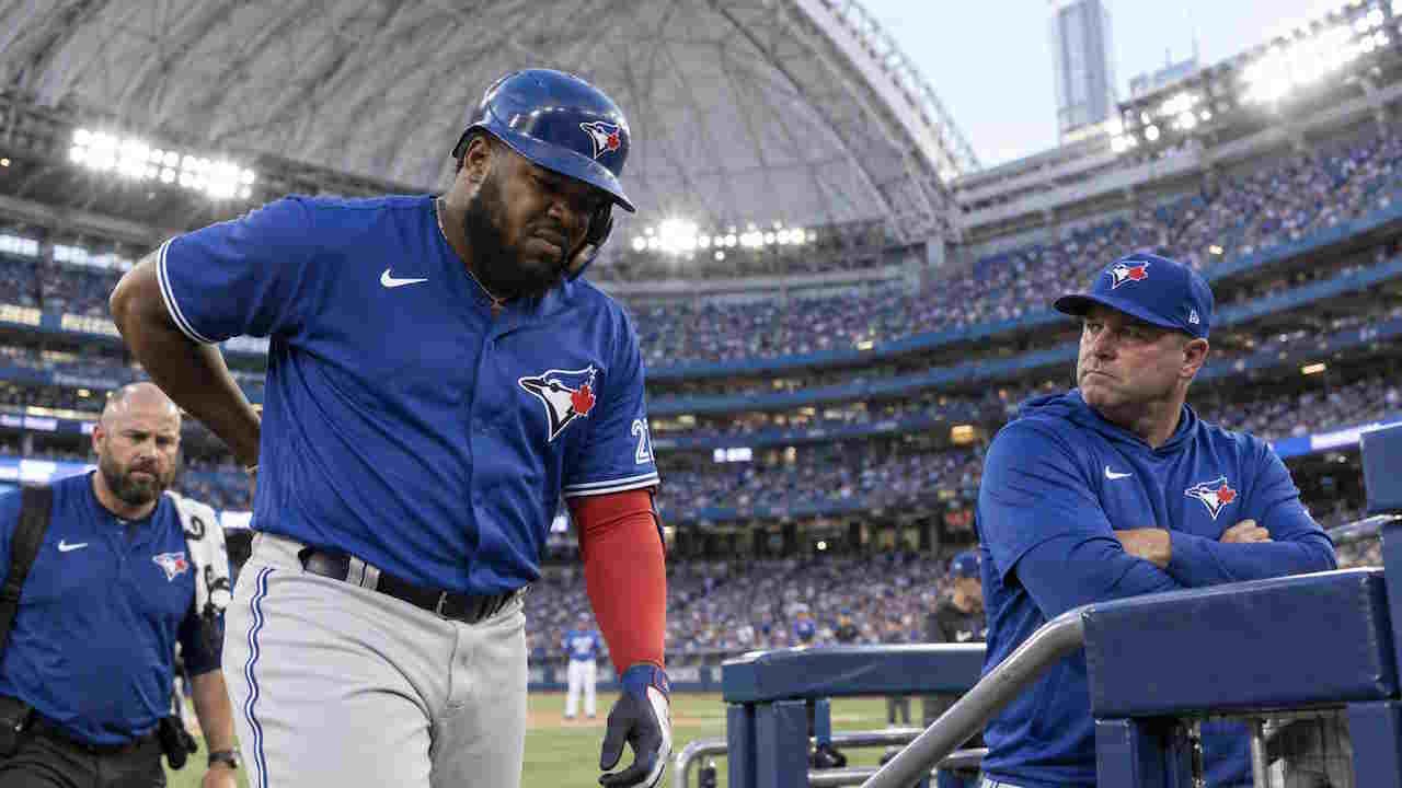 Vladimir Guerrero Jr grimaces in pain as Blue Jays manager John Schneider watches from the dugout